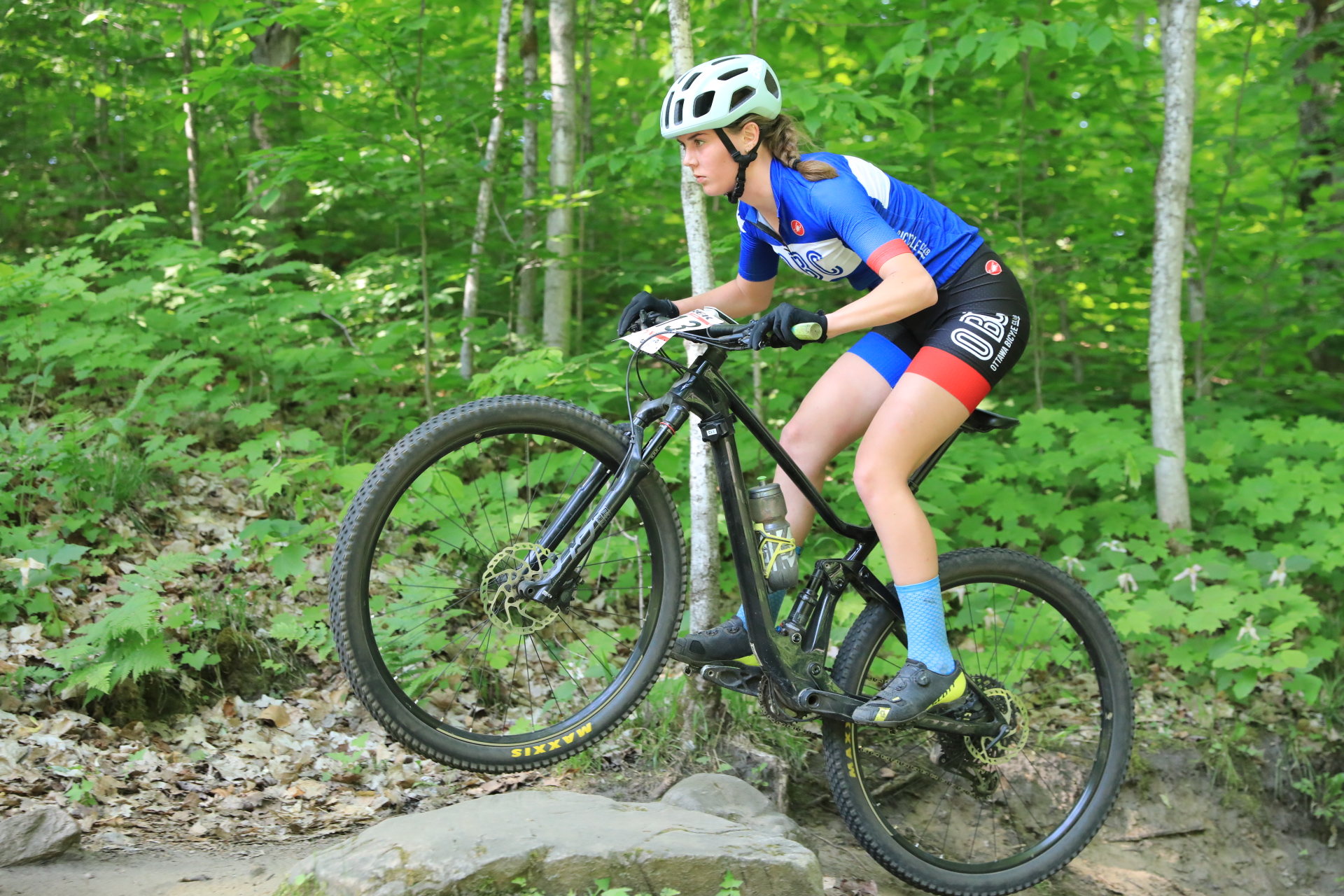 Female mountain bike rider maneuvers over a boulder
