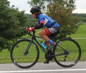 Female cyclist in blue and black Ottawa Bicycle Club Kit enjoying a ride