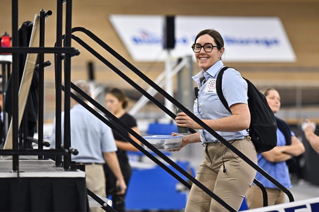 Marie Eve Potvin smiling wearing a blue commissaire shirt ascending a staircase to the commissaire stage