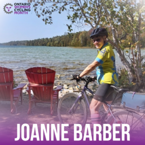 Woman in cycling kit looking over her shoulder smiling with Muskoka chairs and a lake view background text reads Joanne Barber