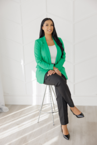 Woman in business attire sitting on a stool facing the camera