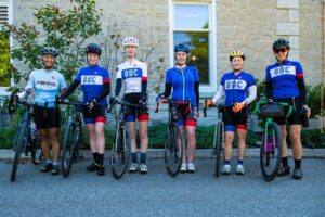 OBC females group photo standing in full OBC cycling kit beside their bicycles smiling