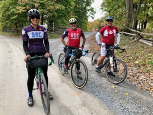 3 master riders pose on a gravel trail in full OBC cycling kit